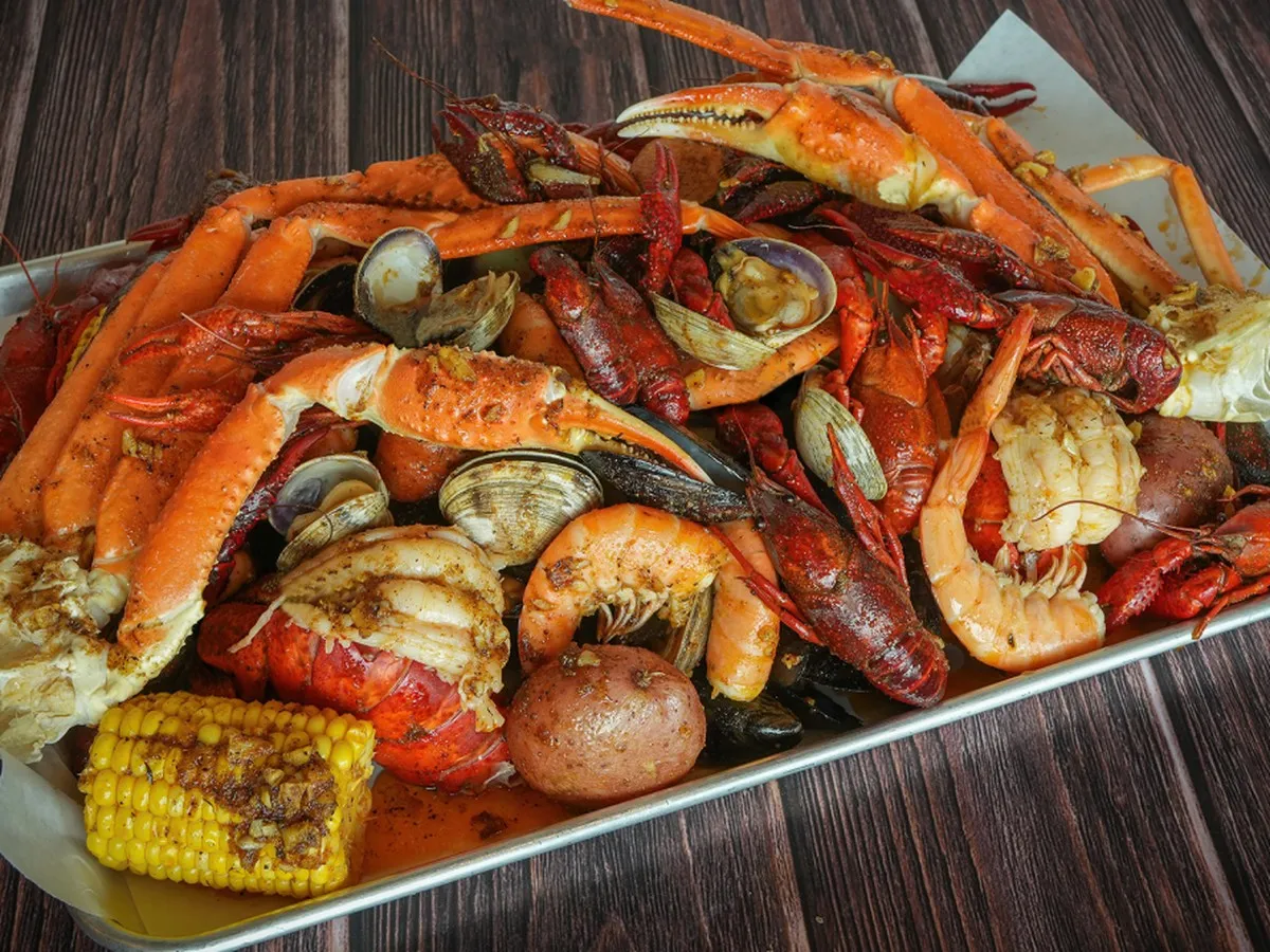 Tray of snow crab legs, crawfish, shrimp, clams, corn and potatoes